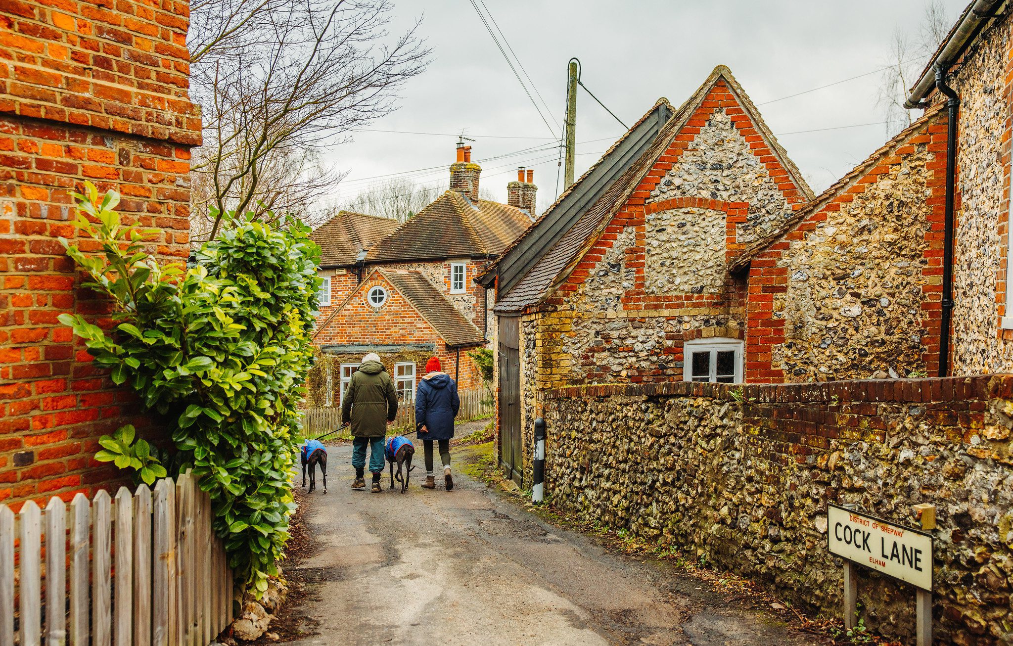 Two people walking down Elham village