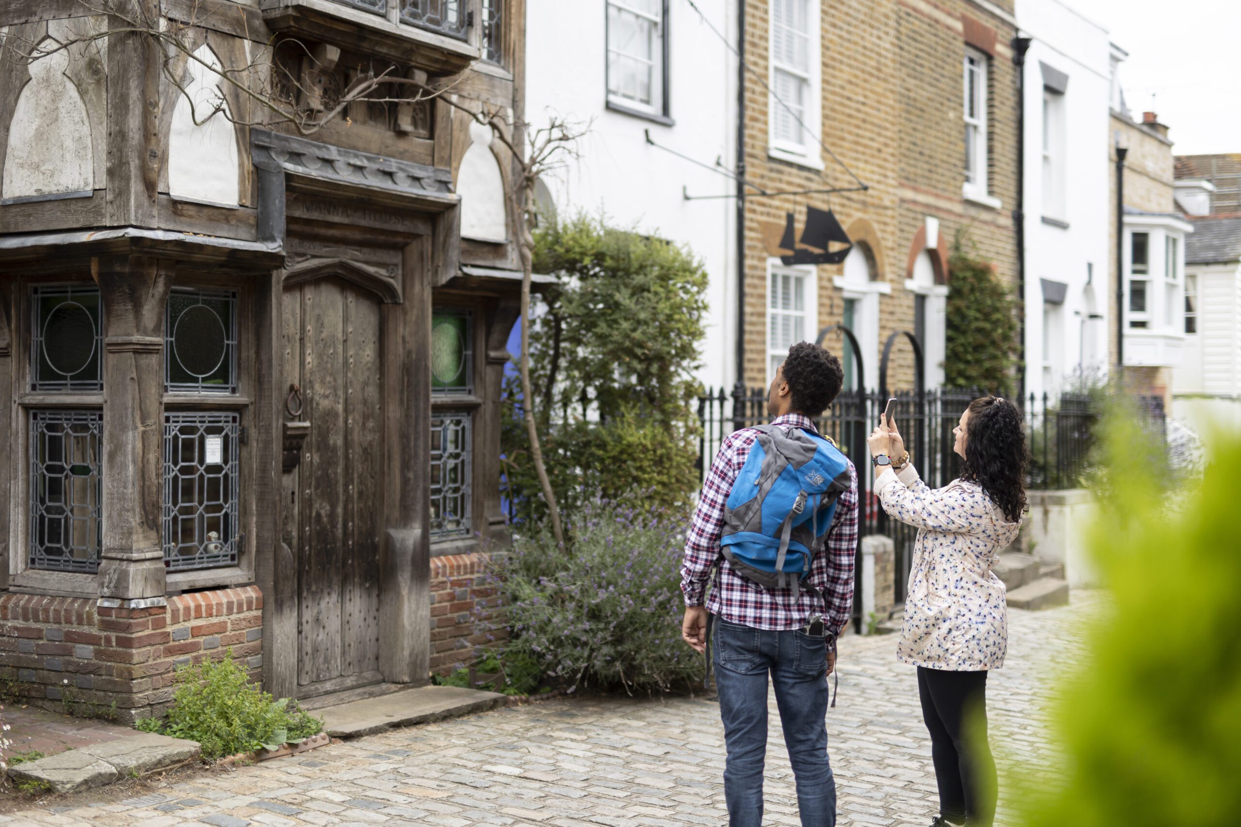 A couple take photos of a pretty house in Upnor Village.