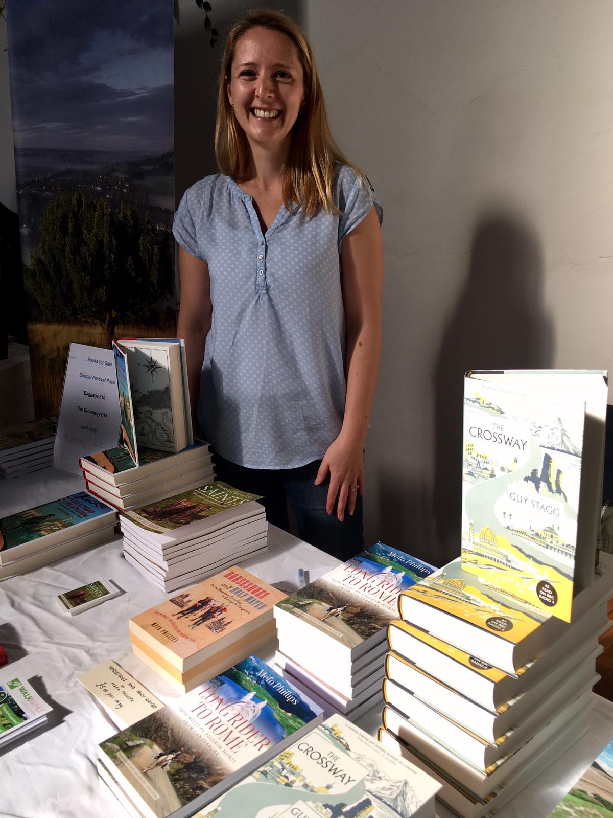 Julia smiling at camera, with books on display table in front of her.