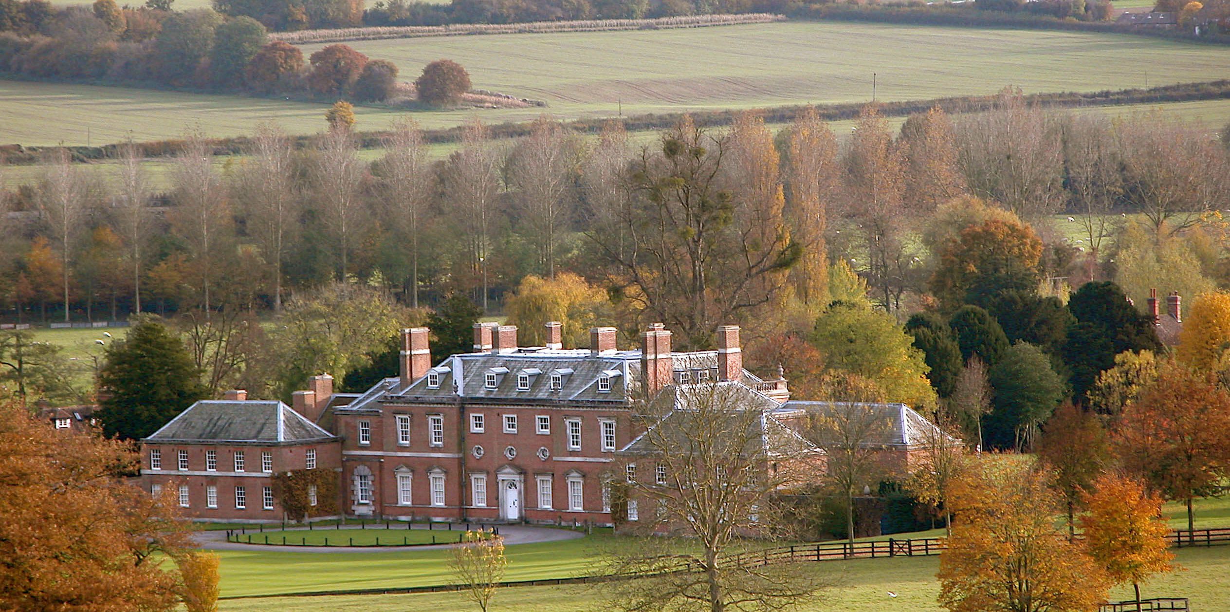 Godmersham House, surrounded by grass fields and trees, in autumn.