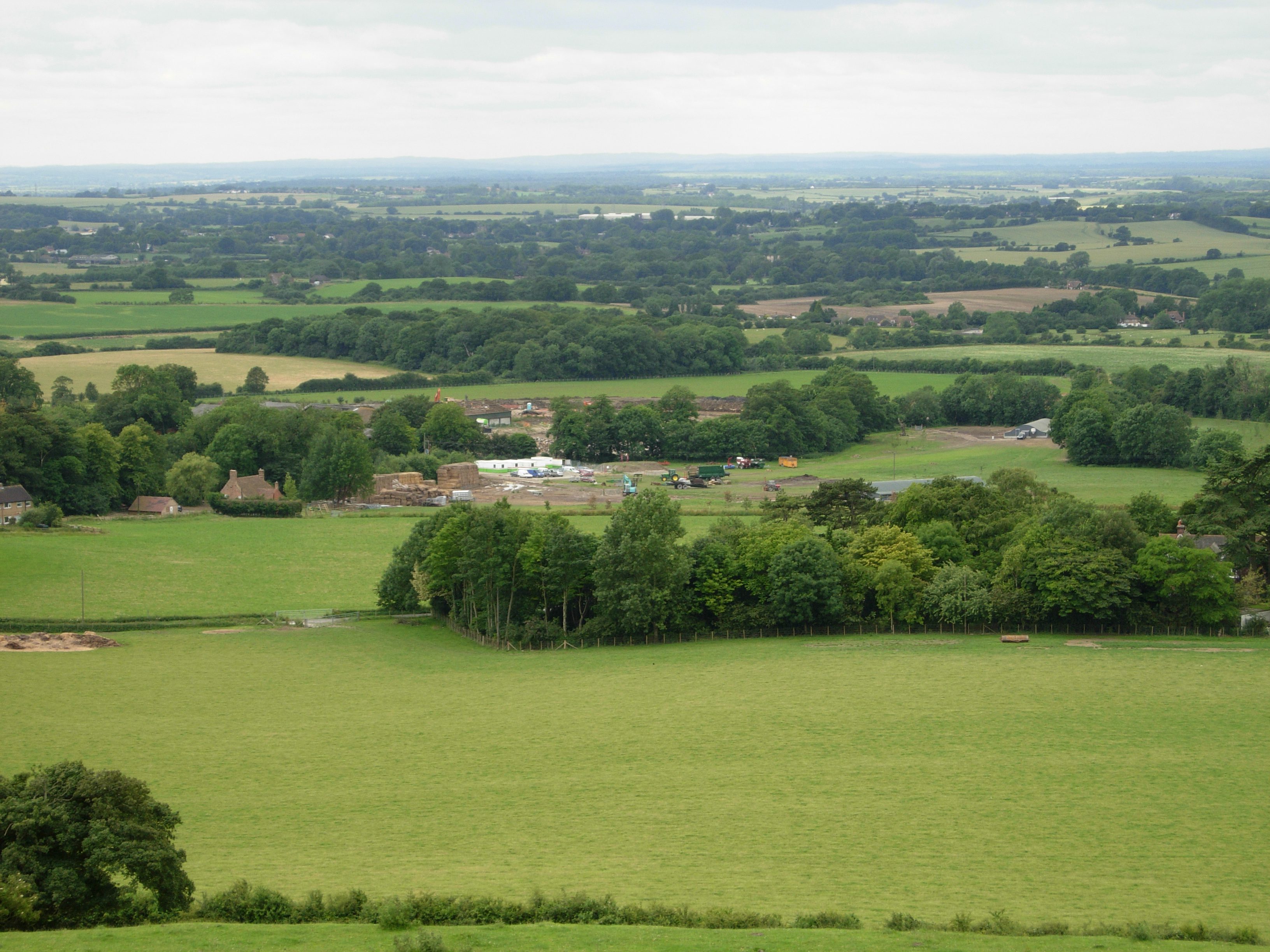 View of green fields, some woodlands and houses in distance.