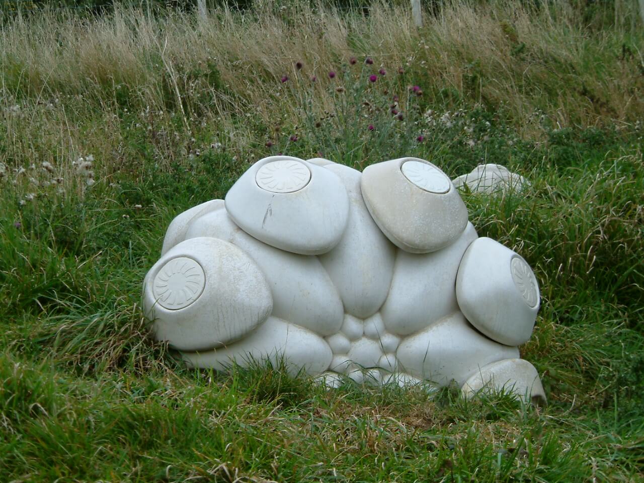 Close-up white sculpture in grass meadow.
