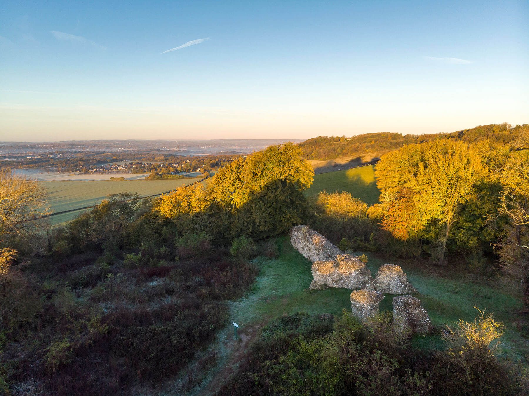 Views across Thurnham Castle ruins, with green and yellow trees on a sunny day.