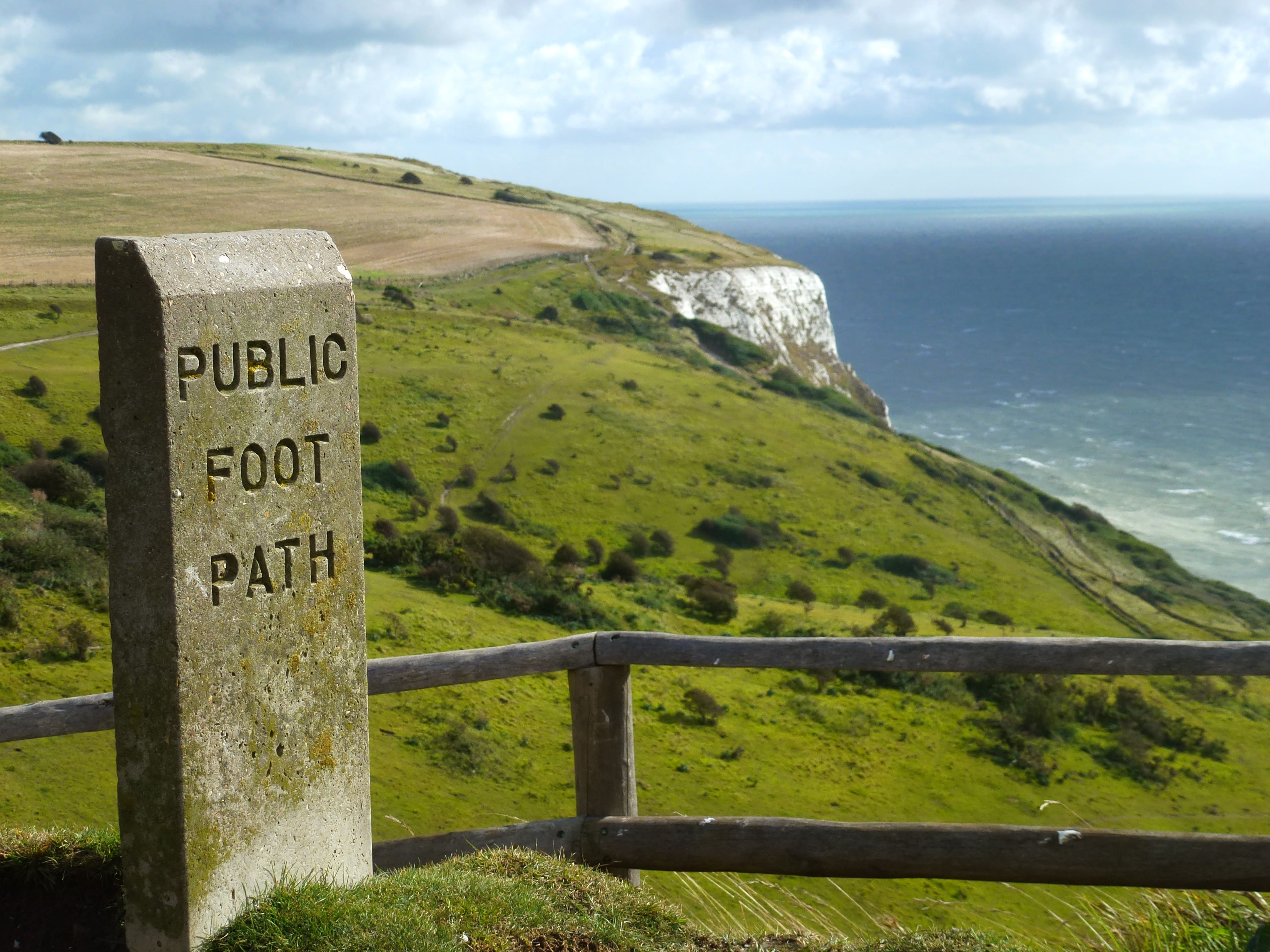 Public foot path sign, overlooking White Cliffs of Dover, with green and sea in the distance.
