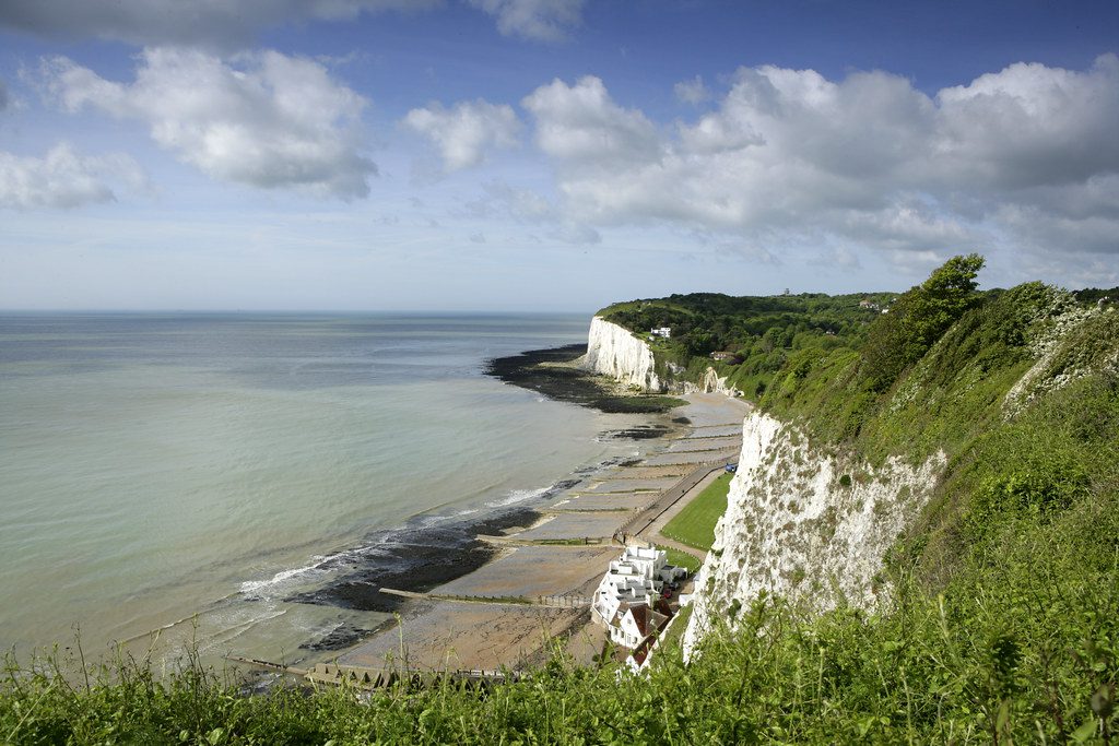 Views of St Margaret's Bay from cliffs. Greenery on top of cliffs, with sea to the left, on a sunny day.