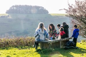 Group of people having picnic on bench, overlooking view of Etchinghill.