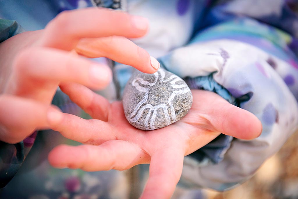 Close-up child holding a rock with white markings.