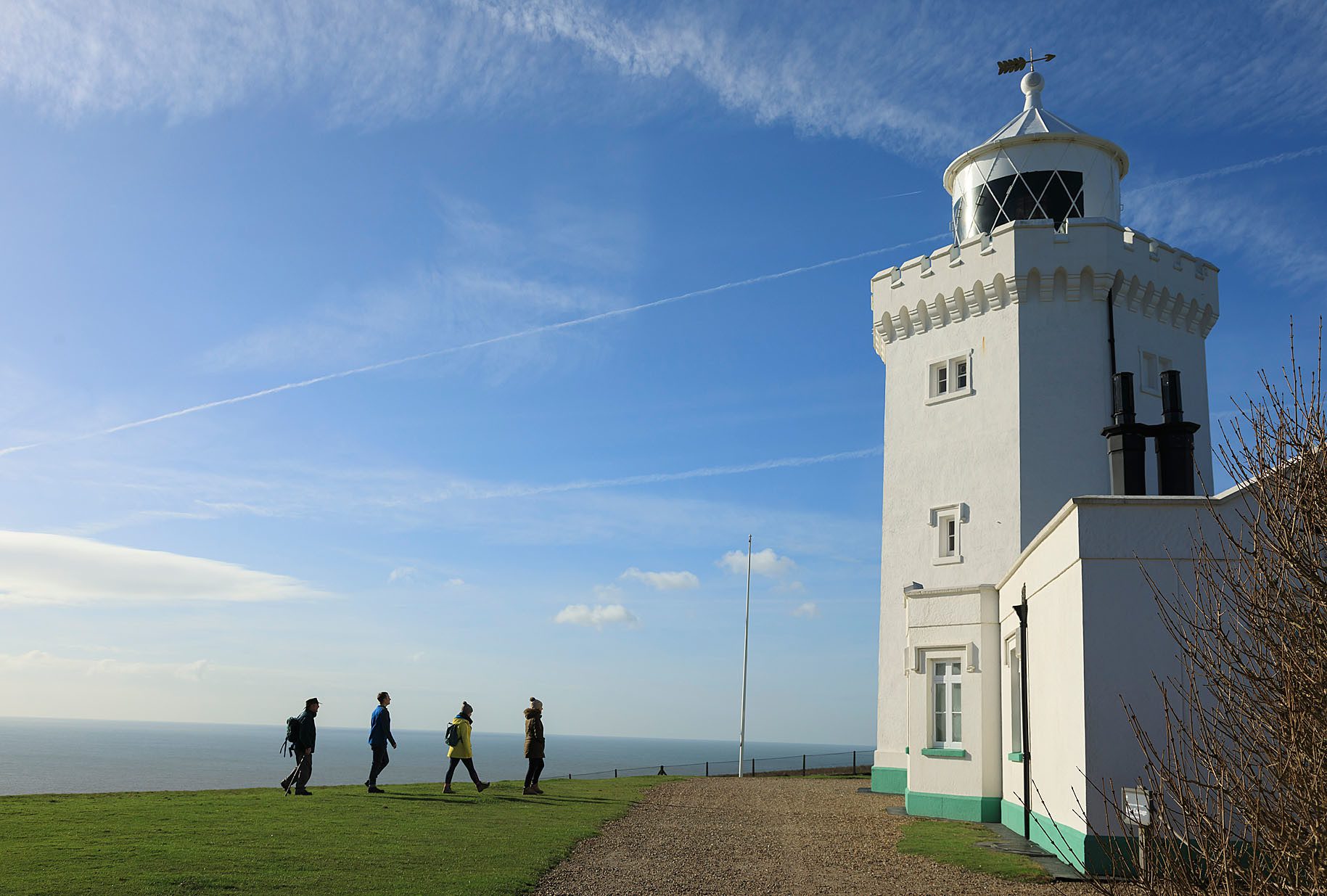 Group of four people walking single-file towards lighthouse