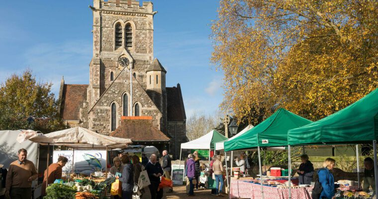 Outside church with food stalls and people walking around, on a sunny day.