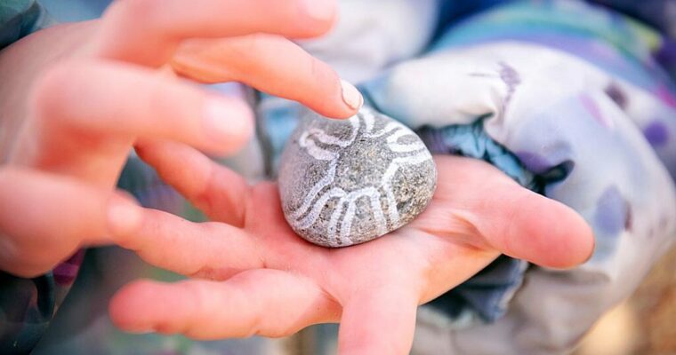Close-up child holding a rock with white markings.