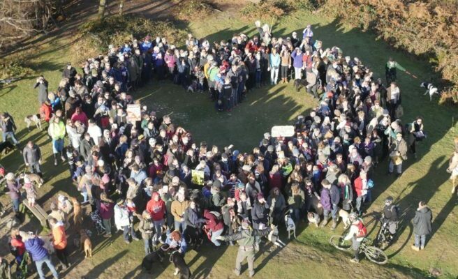 Group of people standing, making a heartshape. Image taken from above.