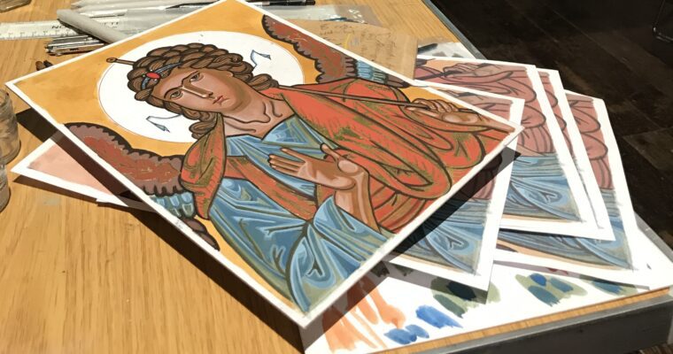 People in a workshop, sitting at tables working. With paints and painted art on table in foreground.