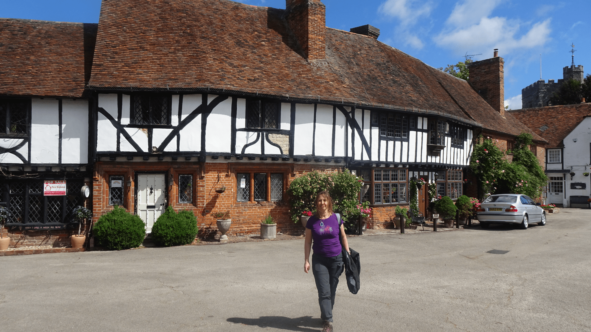 Chilham village street, old timber framed buildings on a sunny day. Person walking towards camera.
