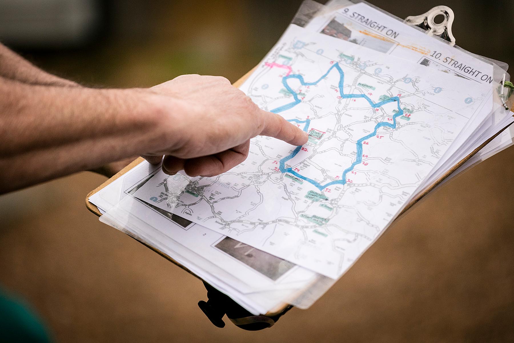 Close-up person pointing to map on a clip board.