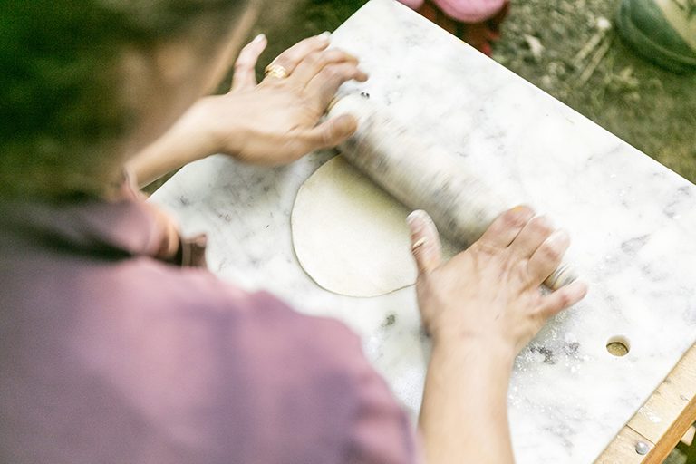 Close-up action image of person using rolling pin to roll pastry.
