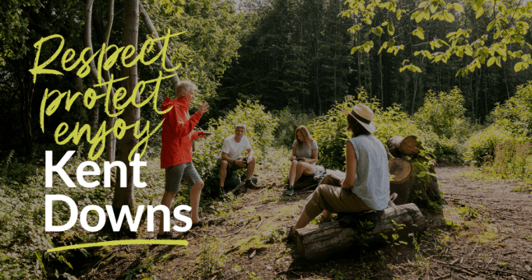 Group of people in woodland clearing, sitting on logs, on standing and talking. With text Respect, protect and enjoy Kent Downs overlayered on image.