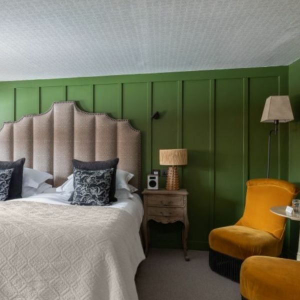 Double room at The Fallstaff Inn. Green wood panel walls, and yellow chairs and small table.
