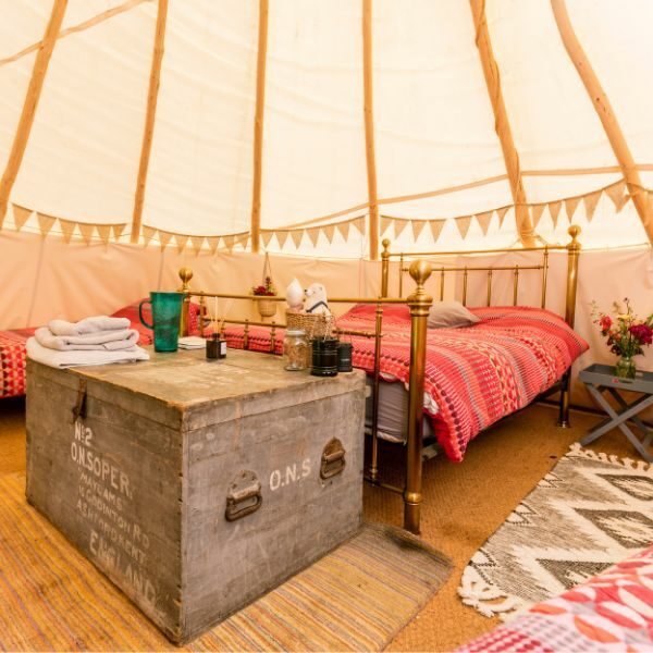 Glamping inside a tent, with double bed and storage trunk.
