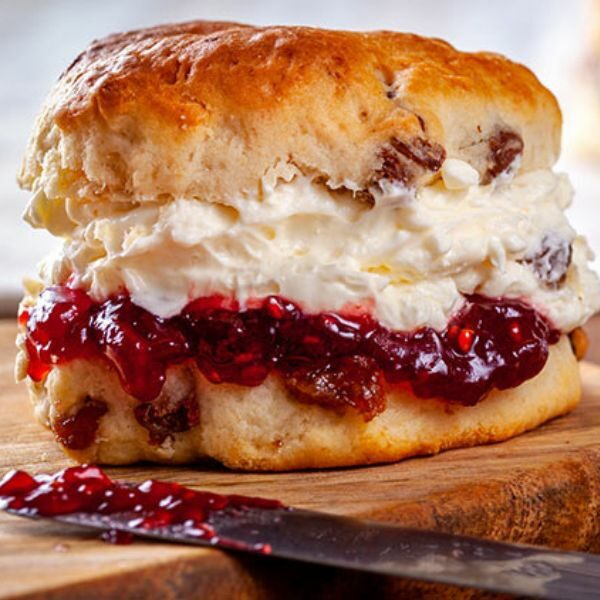 Close-up fruit scone with cream and jam filling.