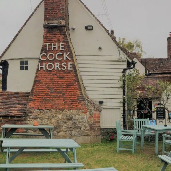 The outside of The Cock Horse pub, with garden benches.