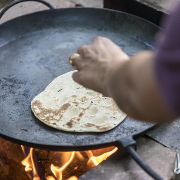 Close-up cooking chapattis over an open fire.