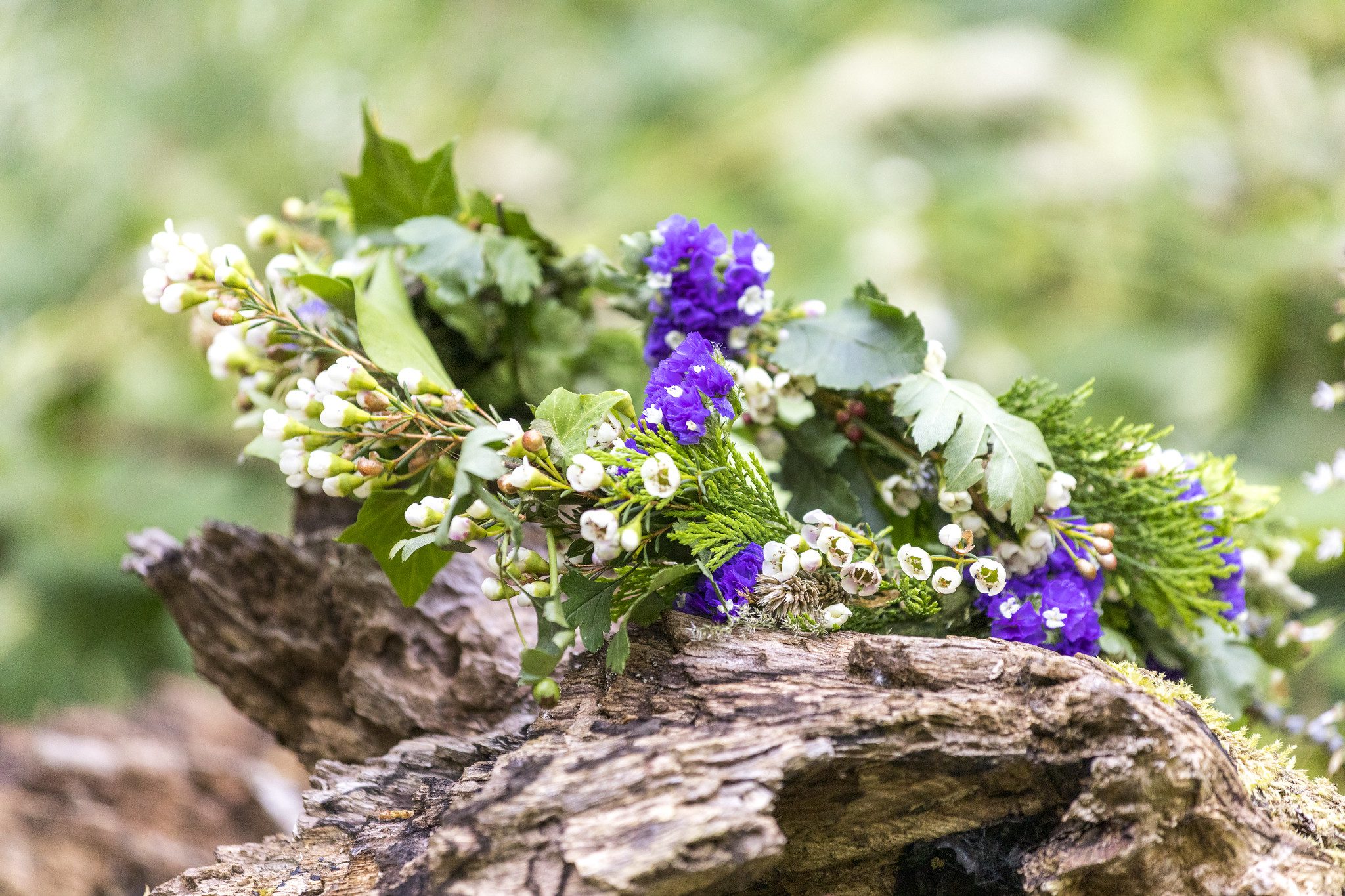 Wreath on a wooden log. Purple, green and white colours.