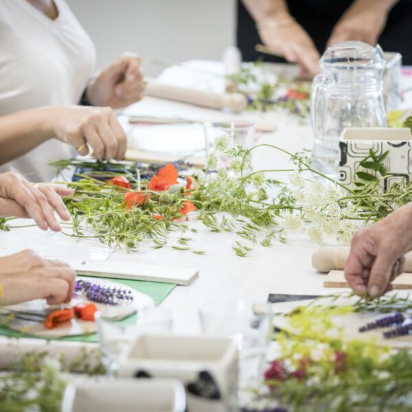 Close-up on people around table, decorating with wild flowers.