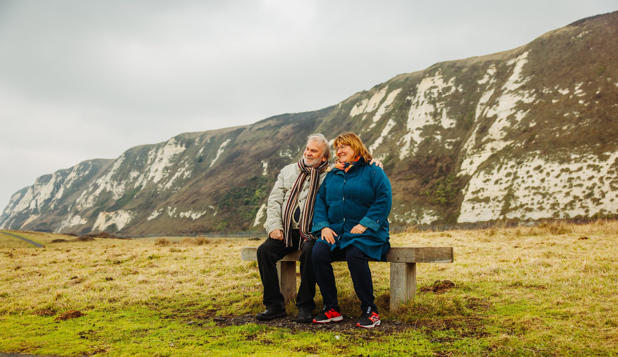 Couple sat on a bench with white cliffs behind