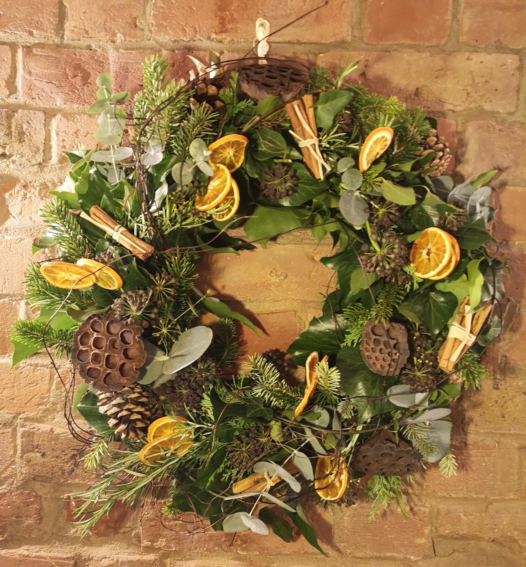 Wreath hanging from brick wall. Orange, green and brown colours.