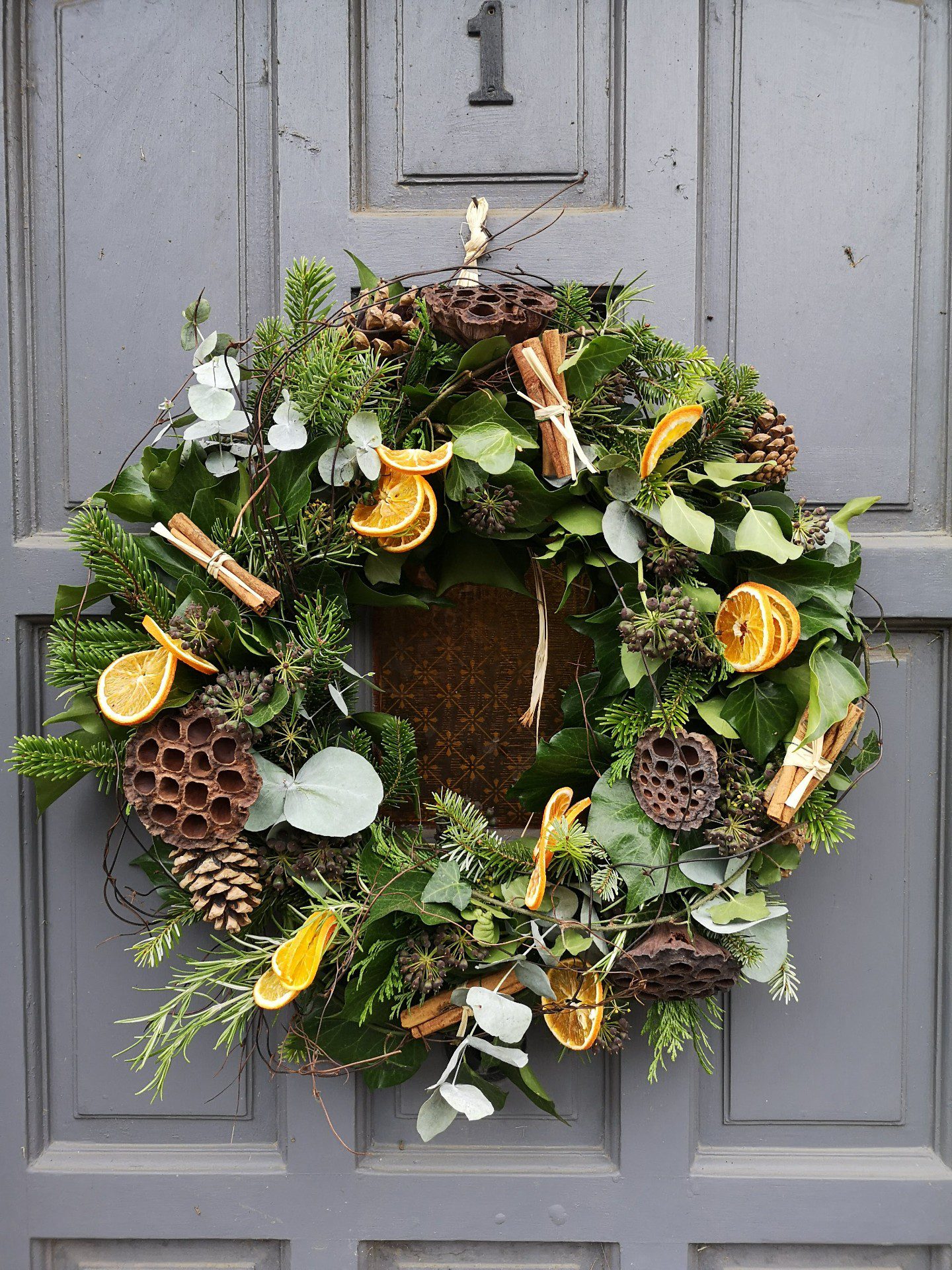 Front door with wreath hanging up. The wreath is green and orange colours.