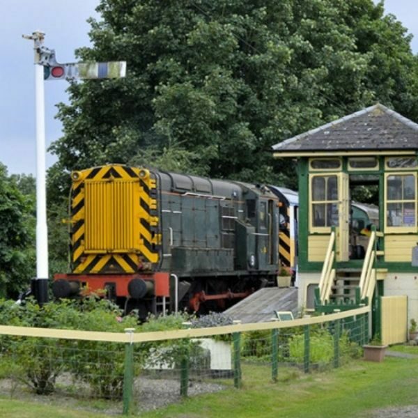 Green and yellow railway signal cabin and stationery train.