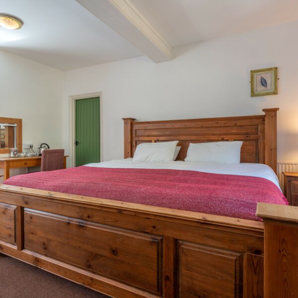 Double bedroom at The Woolpack Inn. Pine bed with white sheets and red cover.