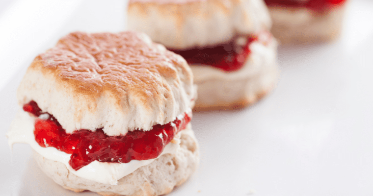 Close-up of plain scone filled with cream and jam.