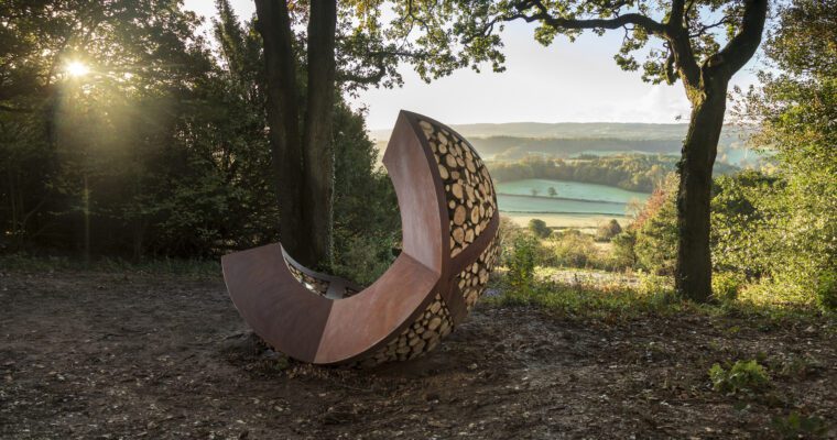 View over Surrey Hills, grass fields and woodland. With Optohedron sculpture in foreground.