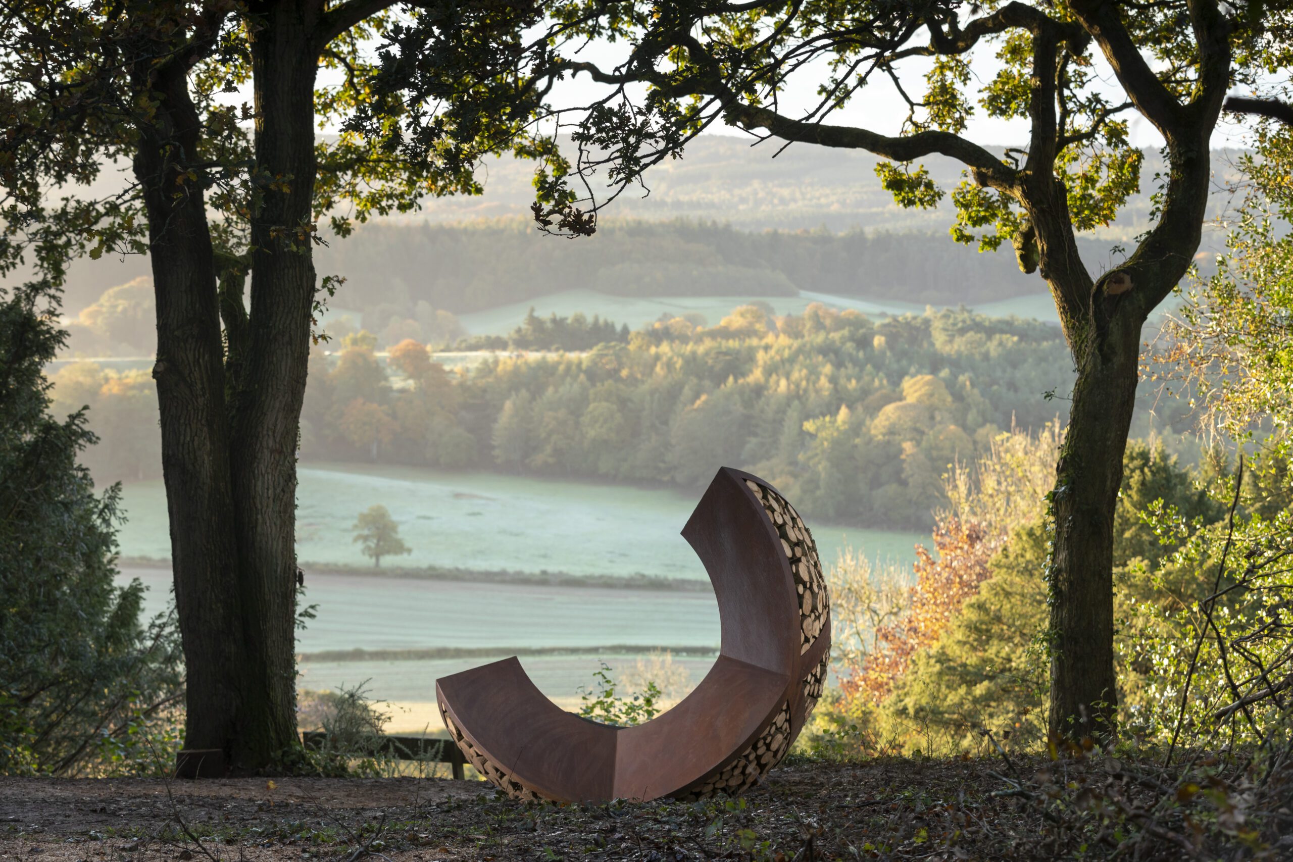 View over Surrey Hills, grass fields and woodland. With Optohedron sculpture in foreground.