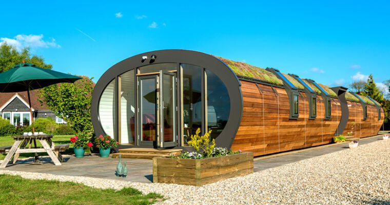 Ground level, oval-shaped eco barn with surrounding garden, lawn and gravel at Bumble Barn.
