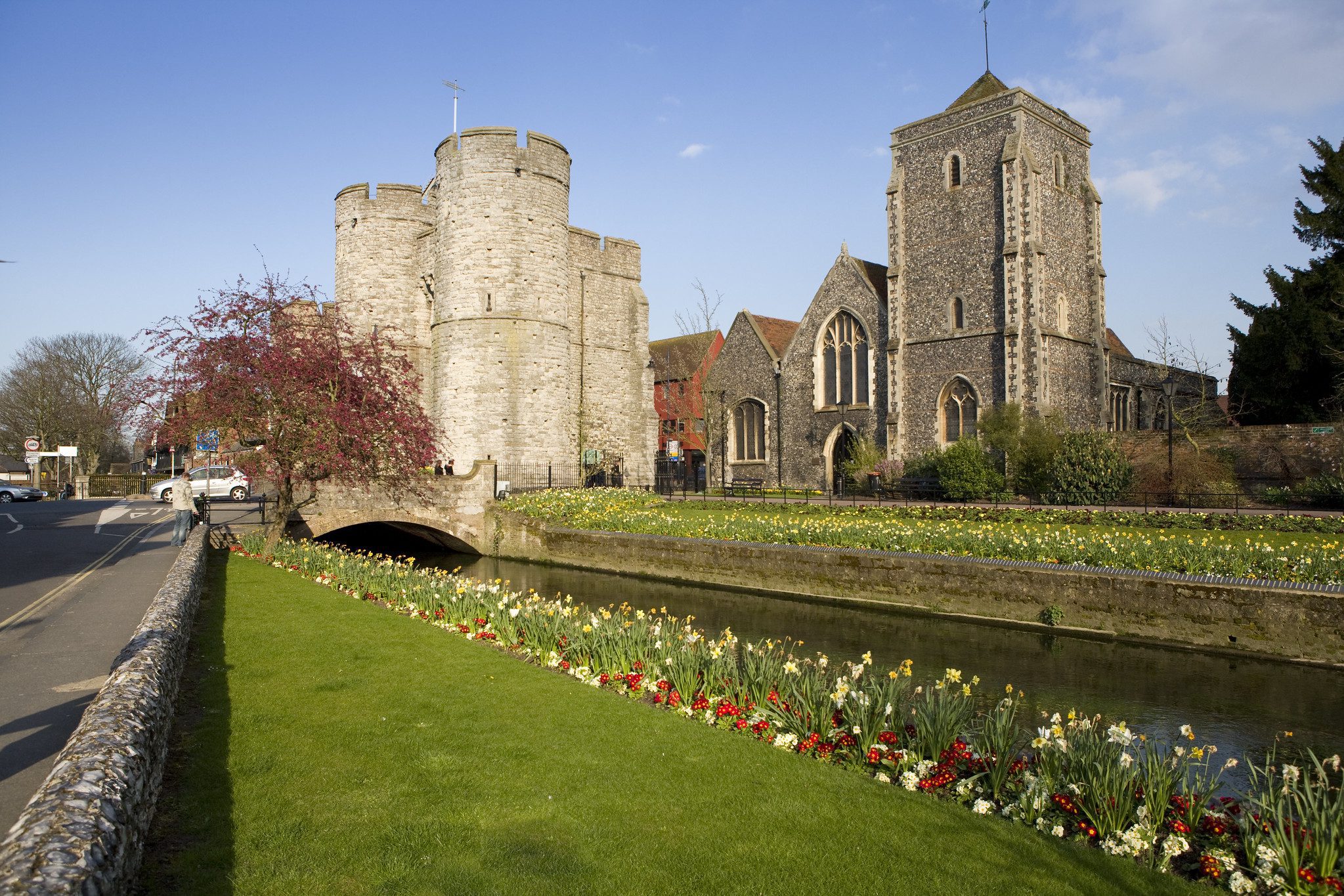 Flowers lining river and historic buildings
