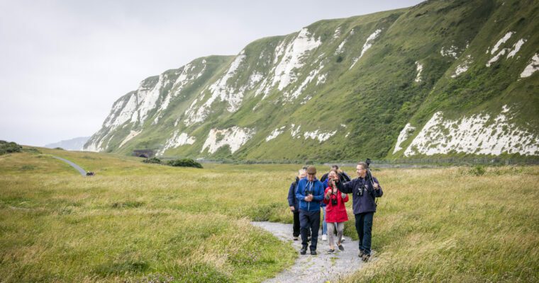 Group of people walking on path, at Samphire Hoe with cliffs to right.
