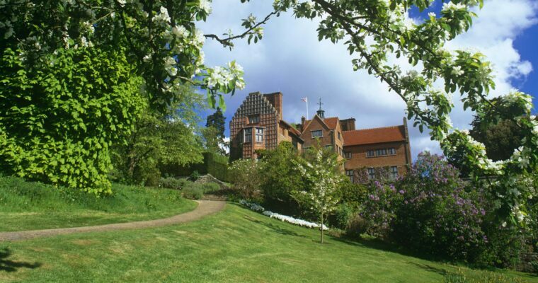 View of Chartwell from the grounds. On a sunny day, with blossom on tree in foreground.