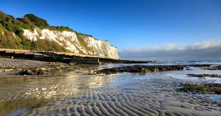 White cliffs and sand ripples at St Margaret's Bay. Cliffs on the right and blue skies.