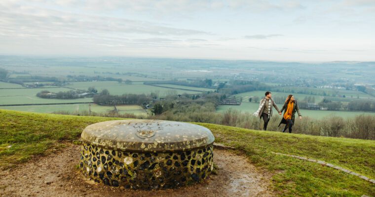 View over Wye Downs, with two people walking. The Floreat Stone or The Millennium Stone is in foreground.