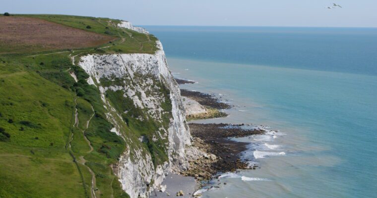 White Cliffs of Dover, with grass on top of cliffs and sea below, on a sunny day.