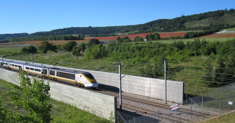 Eurostar train travelling through Kent countryside with fields of red poppies and blue sky