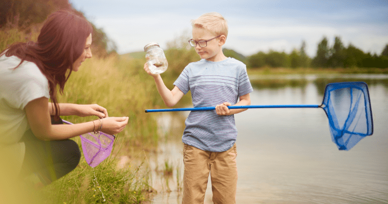 Boy in glasses and mother pond dipping with blue net