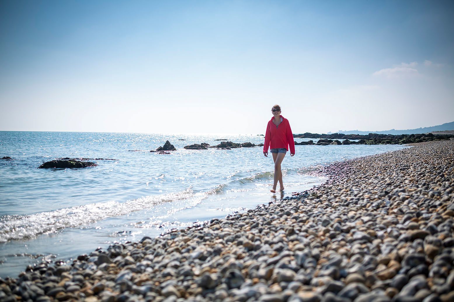 Woman walking along shore of shingle beach