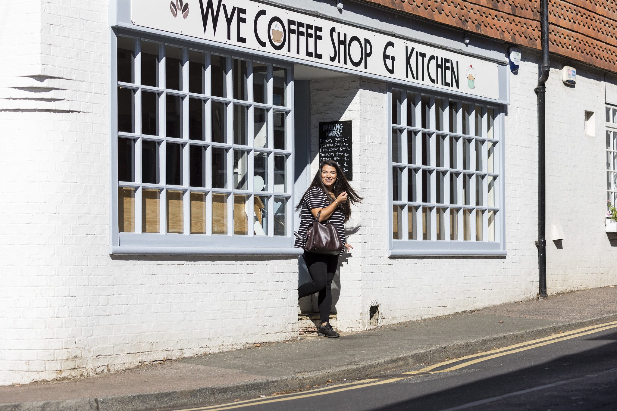 Smiling woman emerging from Wye coffee shop