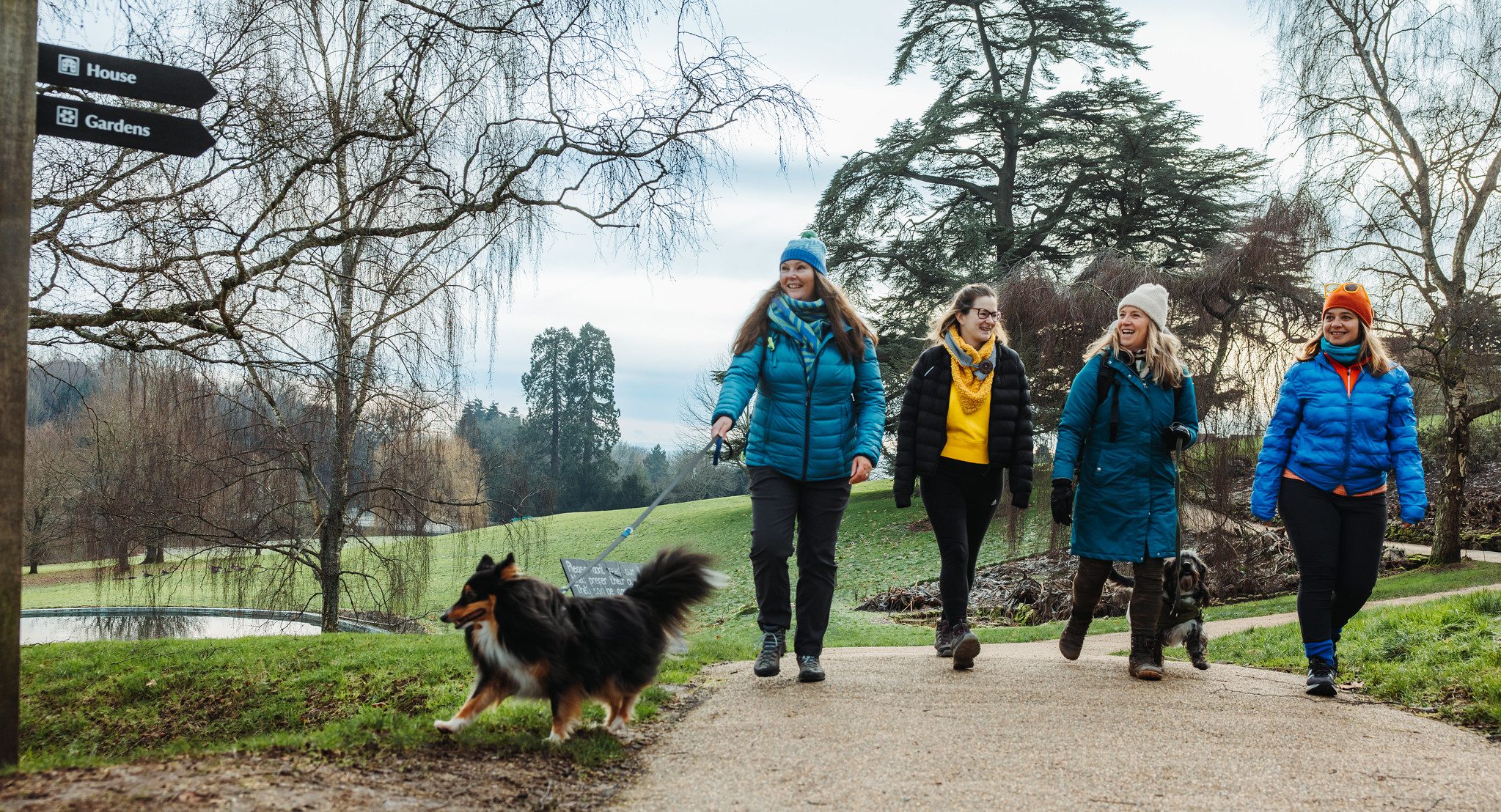 Four women in winter coats walking dogs through grounds of Chartwell House