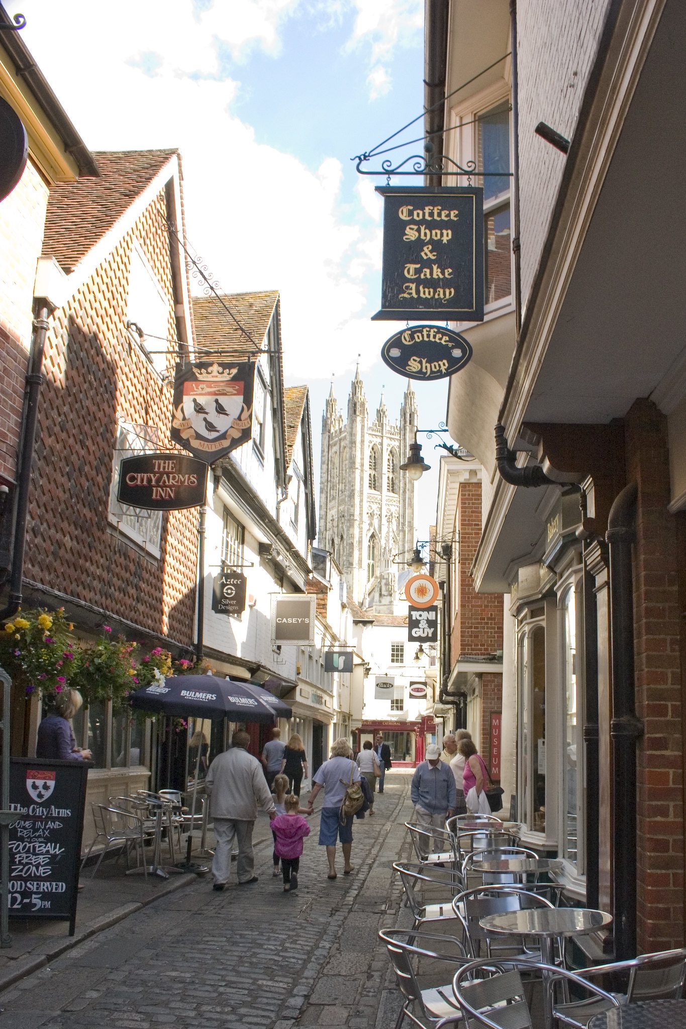View down a cobbled lane with shops and cafe tables on either side