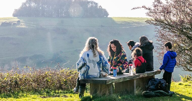 Group of people having picnic on bench, overlooking view of Etchinghill.