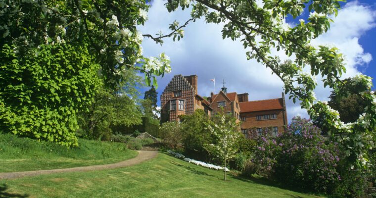 View of Chartwell from the grounds. On a sunny day, with blossom on tree in foreground.